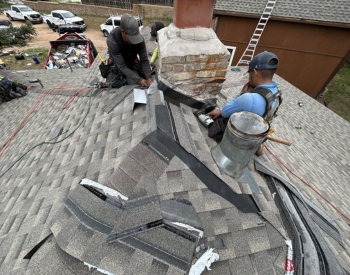 Roofer repairing flashing around a chimney in Spring, TX